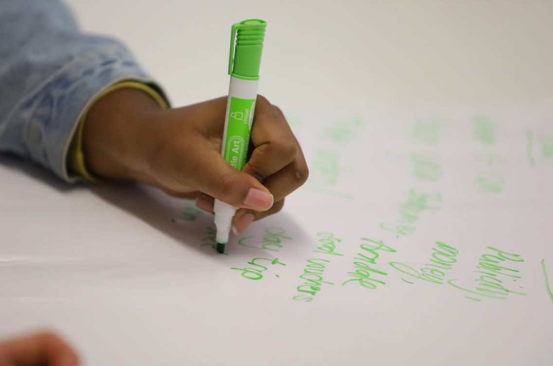 Writing on a whiteboard with a green marker pen.