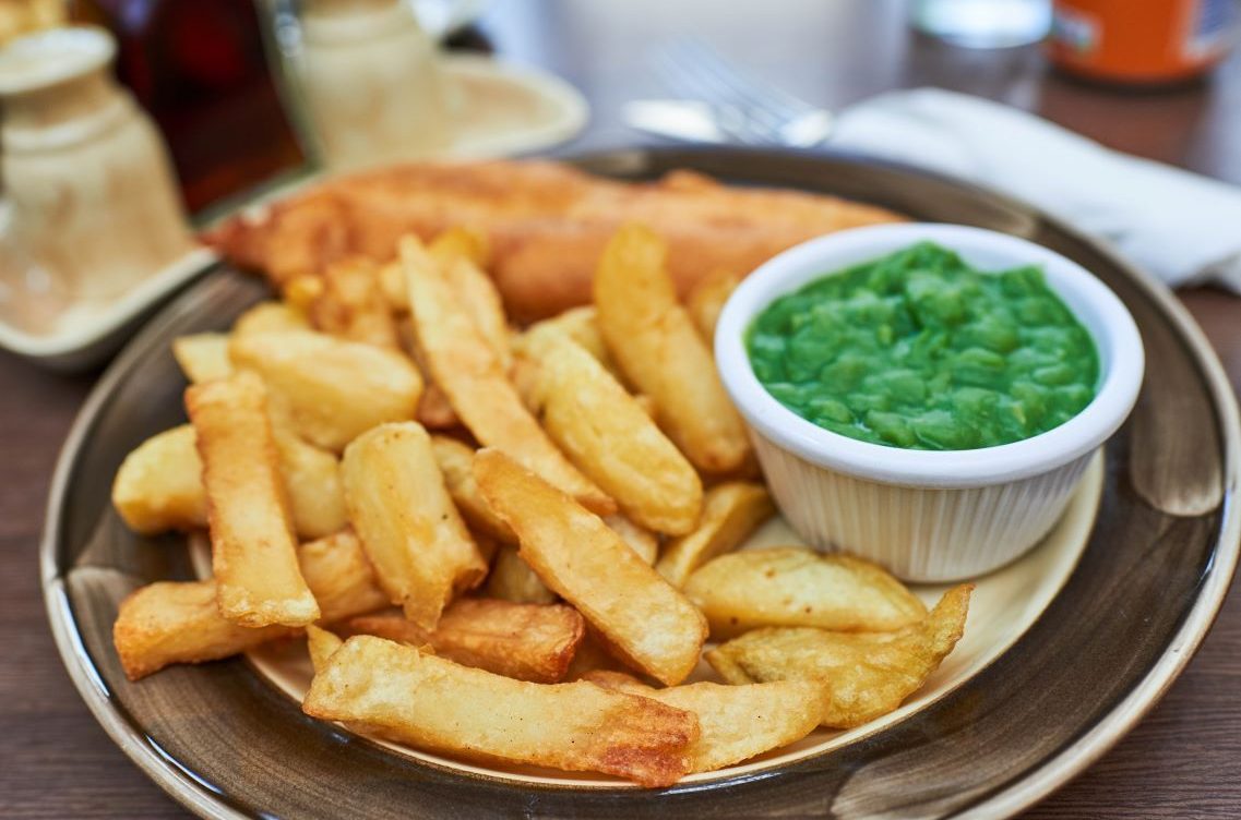 Fish, chips and mushy peas on a plate.