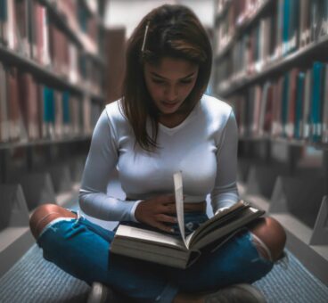 Girl reading sat on floor in Library